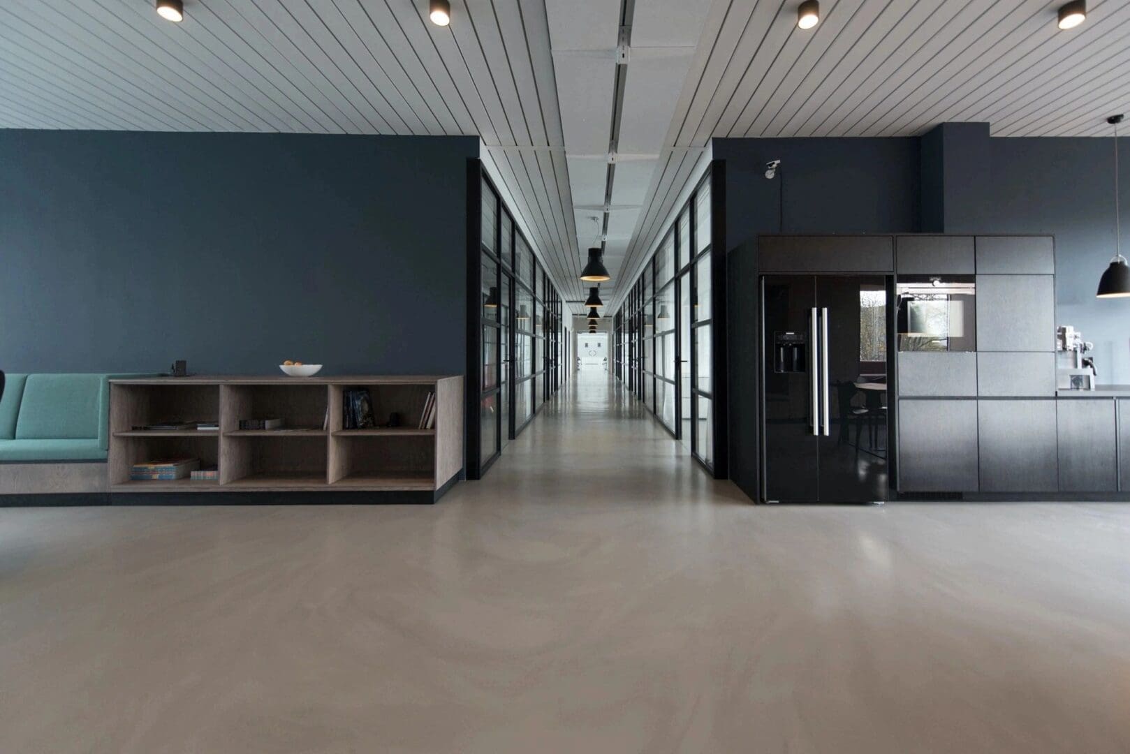 A long hallway with glass walls and black cabinets.