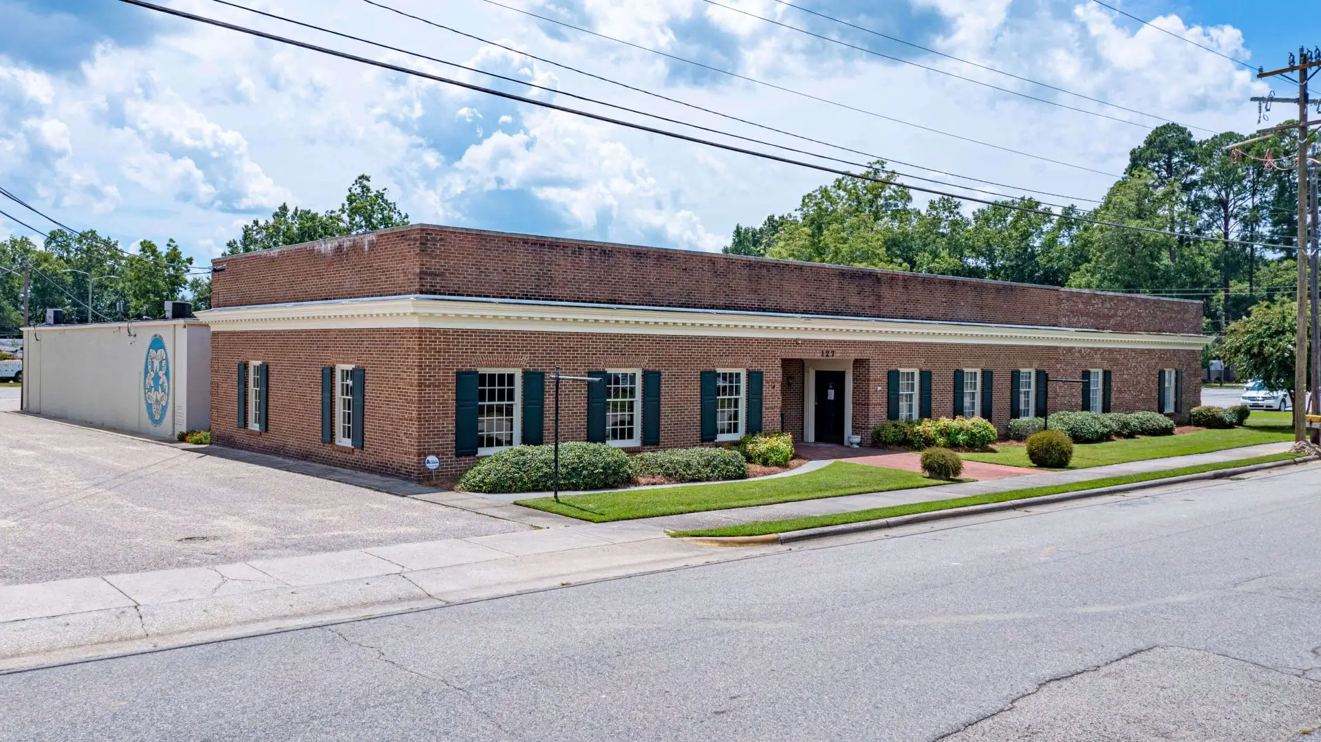 NEWS-REPORTER-25-scaled Brick building with landscaping and parking.