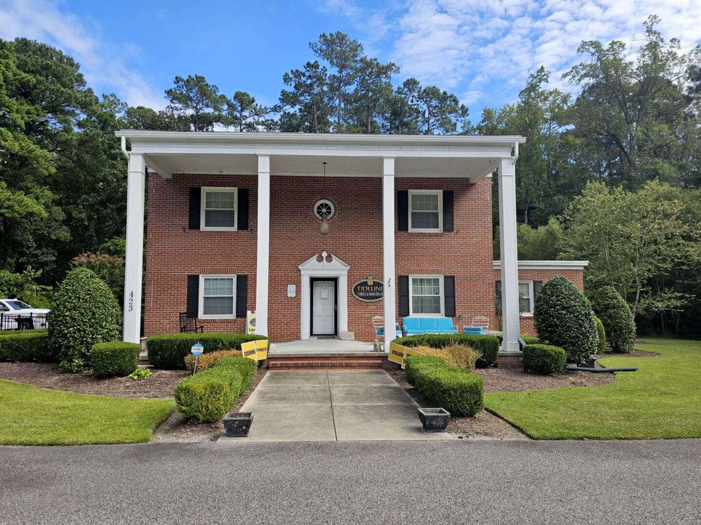 Brick building with columns and green shrubs.